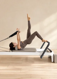 Client holding a side plank position on a Pilates reformer